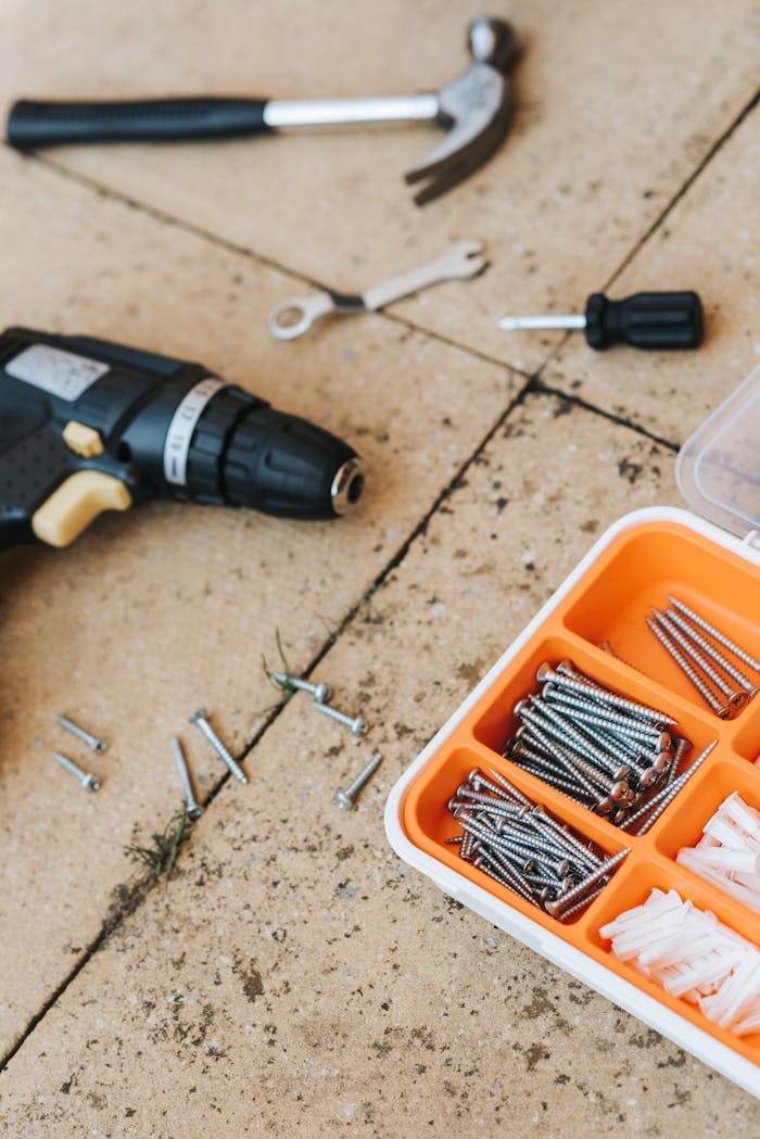 From above of assorted carpentry tools in plastic case placed with metal hammer and screwdriver